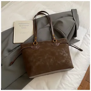 Détail d'un grand sac cabas en daim marron avec cordon latéral et anneaux métalliques