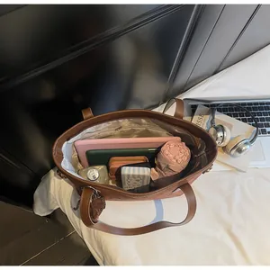 Top view of large brown tote bag interior with tablet, notebook, wallet, and umbrella