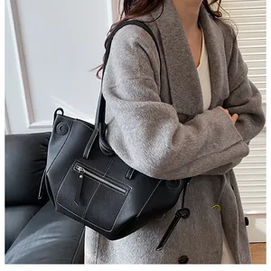 Close-up of black leather wing tote with white contrast stitching and zip pocket details