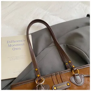 Gros plan du sac cabas en similicuir marron avec étiquette de marque et rivets en bronze