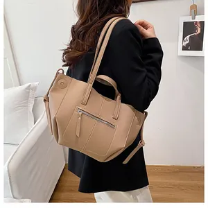 Detail of beige litchi grain tote bag with front zipper and side drawstring on model