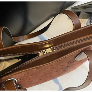 Detail view of cartoon bear embossed tote bag with smooth brown leather handle and zipper