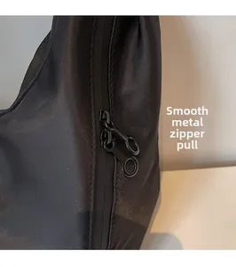 Detail of smooth metal double zippers on black nylon shoulder bag with premium hardware