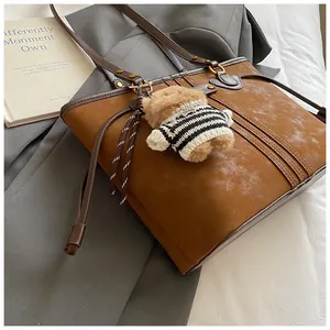 Vue détaillée d'un cabas caramel avec poignées marron et un charmant petit ours en peluche