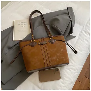 Gros plan du sac cabas en daim marron avec anneaux dorés et détails de franges