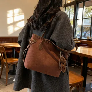 Brown embossed tote bag with teddy bear pendant shown on model in cafe setting