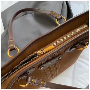 Détail du cabas en cuir marron foncé avec fermeture éclair dorée et logo embossé