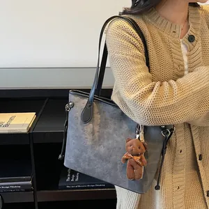 Dark grey embossed tote bag with puppy patterns, leather straps and a plush bear charm