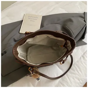 Vue de dessus du grand sac cabas en cuir marron avec doublure grise et charm en peluche