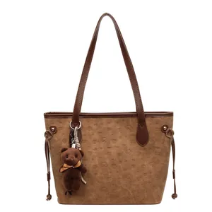 Brown cartoon embossed tote bag with teddy bear charm and drawstring details