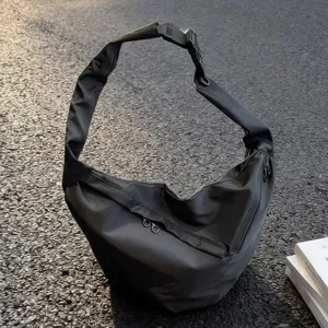 Large black Oxford fabric crossbody dumpling bag with wide shoulder strap in sunlight