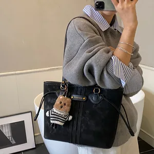 Sac cabas noir mat élégant avec rayures verticales et charm ours mignon porté à l'épaule
