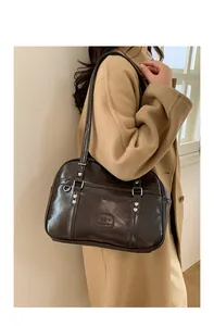 Détail du sac en cuir marron foncé avec rivets cœur argentés et logo embossé chic