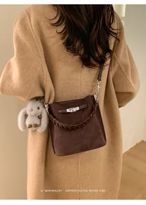Close-up of minimalist brown bucket bag with plush rabbit charm and woven strap