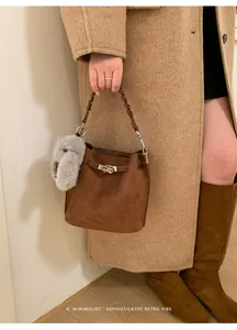 Detail of retro brown suede bucket bag with silver twist lock and braided handle