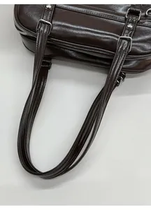 Détail des lanières en cuir PU marron foncé et de la boucle en métal argenté du sac