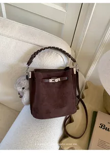 Detail of dark brown suede bucket bag featuring woven handle and silver metal turn-lock