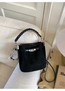 Detail of retro black bucket bag with woven handle and plush pompom charm decoration