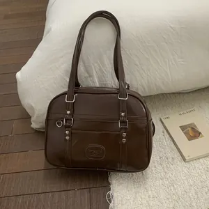 Détail du sac en similicuir marron foncé avec rivets cœur et boucle au style vintage