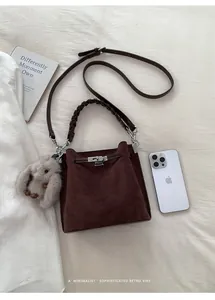 Detail of dark brown suede bucket bag with silver clasp and cute rabbit pendant