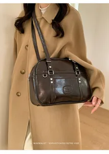 Détail du sac à bandoulière rétro marron foncé avec rivets cœur et logo embossé