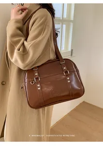 Gros plan d'un sac en cuir PU marron avec boucles en cœur argentées et logo embossé