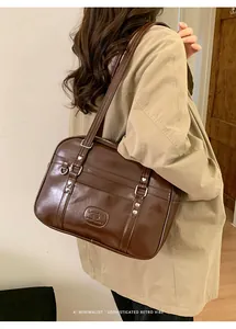Détail d'un sac à bandoulière marron rétro avec rivets coeur et finition brillante