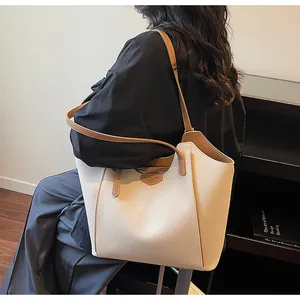 Detail view of large cream tote bag with brown straps worn on shoulder by model