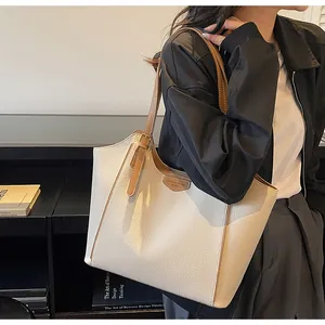 Close-up of litchi texture tote bag with leather tag and metal zipper detail