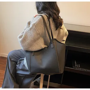 Detailed view of dark grey lychee pattern leather tote bag shown on a shoulder