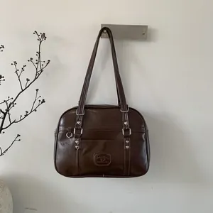 Détail du sac en cuir marron avec clous en forme de cœur argentés et sangles