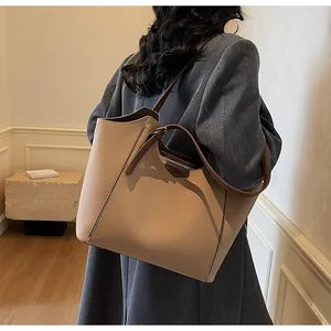 Close-up of beige lychee grain leather tote bag with elegant brown handle and wavy cut edges