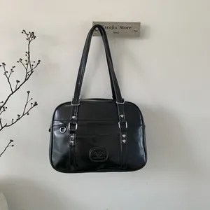 Détail d'un sac d'épaule style JK noir avec rivets en forme de cœur argentés et anneau D