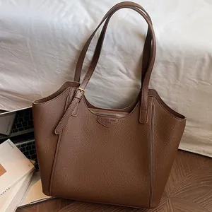 Brown lychee leather tote bag with adjustable straps in a cozy lifestyle setting