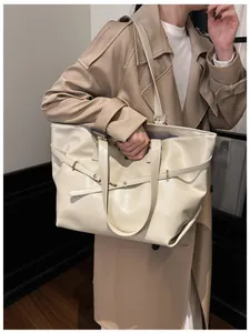 Dettaglio della borsa tote crema con fibbie decorative e texture in pelle pregiata