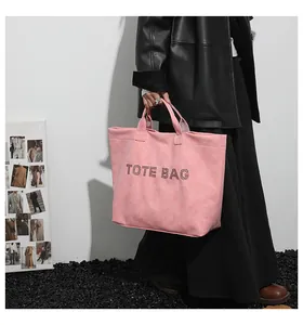Detail of pink faux suede tote bag with black rhinestone TOTE BAG lettering detail