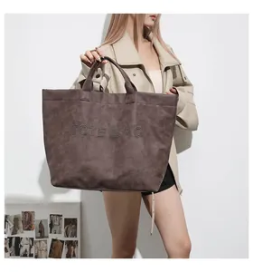 Detail of dark brown tote bag featuring metallic stud lettering and suede texture