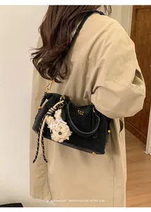 Detail of black retro shoulder bag with gold logo, woven cord and plush bunny charm