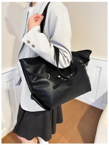 Vista laterale di una grande borsa tote nera in ecopelle con dettagli dorati e modello