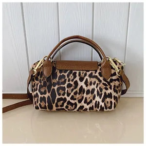 Detail einer kleinen Handtasche mit Leopardenmuster, braunem Leder und Goldbeschlägen