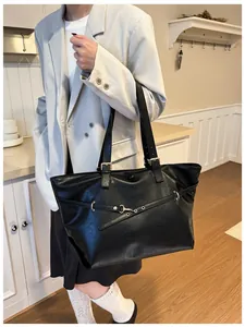 Dettaglio della grande borsa tote in pelle nera con gancio metallico e trama fine