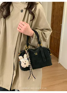 Detail of black suede Boston bag featuring golden logo and cute white plush bunny charm