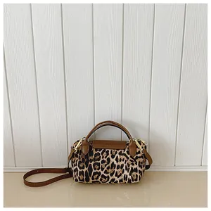Detail der Crossbody-Tasche mit Leopardenmuster, braunen Ledergriffen und Goldbeschlägen