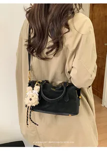 Detail of black suede Boston bag with gold ring hardware and cute plush bunny charm