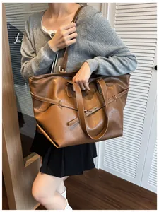 Dettaglio di una borsa tote grande in ecopelle marrone con anelli in metallo e trama morbida