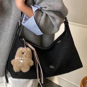 Retro black leather hobo bag with teddy bear charm and sleek half-moon shoulder design