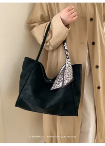 Close-up of minimalist black leather tote bag with stylish paisley scarf detail