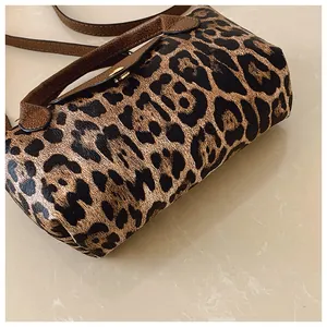 Detailaufnahme der Handtasche mit Leopardenmuster, braunem Ledergriff und Metallschnalle