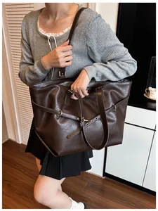 Dettaglio di borsa tote in pelle marrone scuro con anello metallico e fibbia