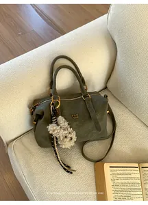 Close-up of retro green leather Boston bag with plush rabbit charm on a sofa